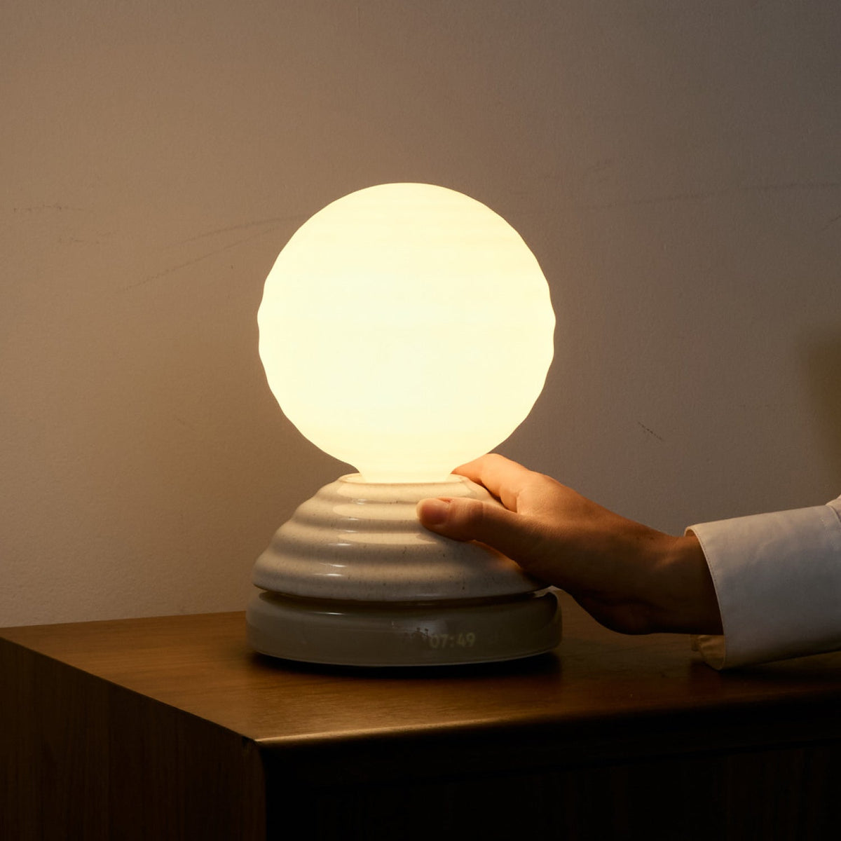 Hand controlling the turn control base of the Wake Sleep Light by Tala Lighting.