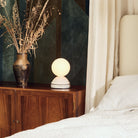 The Wake Sleep Light by Tala Lighting in pebble white on a bedside table.