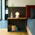 The Wake Sleep Light by Tala Lighting in pebble white next to a bed.