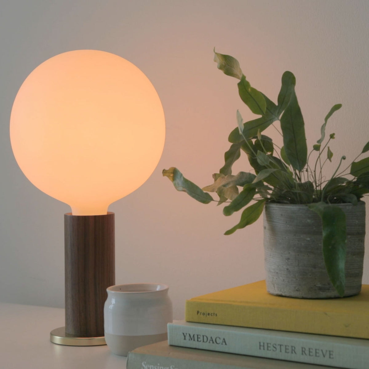 The Sphere IV E26 Dim-to-Warm LED Bulb by Tala Lighting in a walnut table base.
