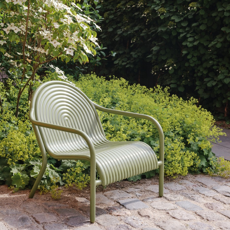 The Groove Outdoor Lounge Chair by Tom Dixon in Moss on a garden terrace.