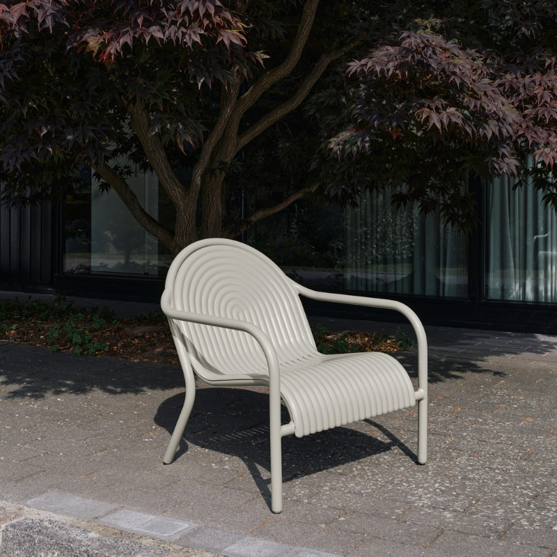 The Groove Outdoor Lounge Chair by Tom Dixon in Putty on a patio.