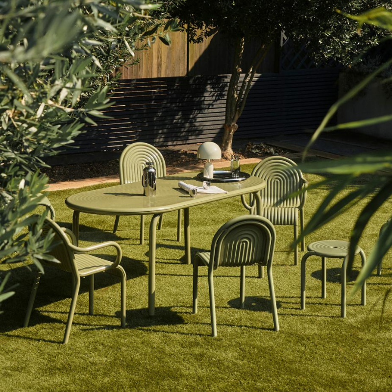 Outdoor patio set with Groove table and chairs by Tom Dixon on a grassy area.