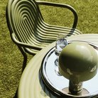 Outdoor setting with a Groove chair, glass of water, and Portable Bell Table lamp on a Groove table.