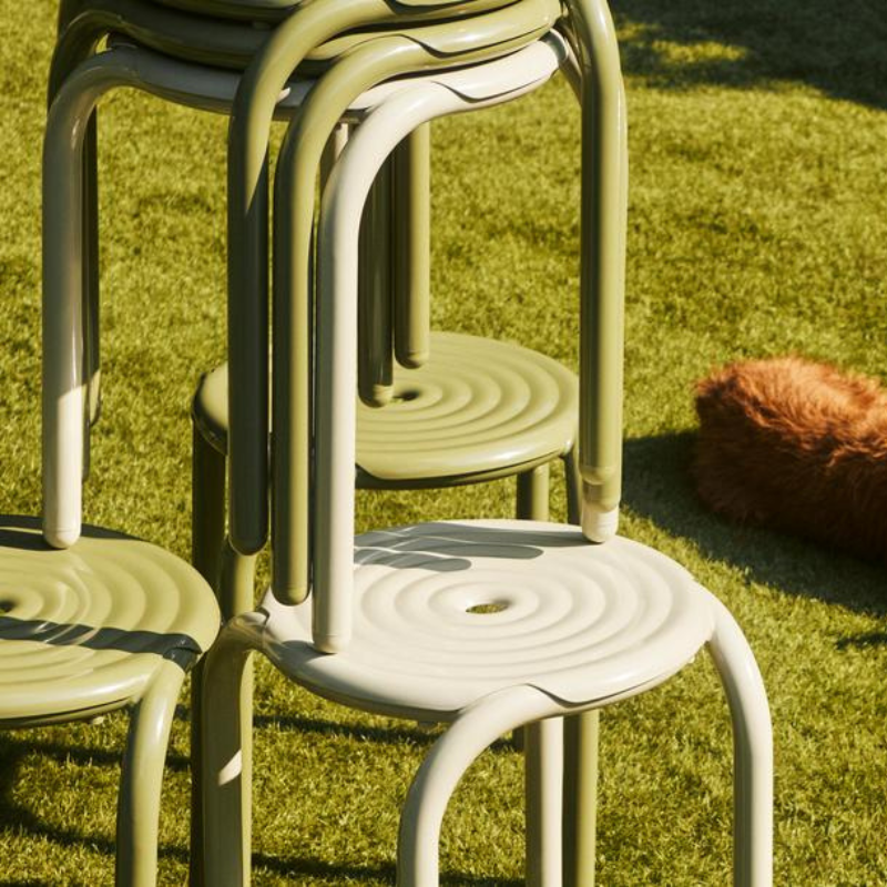 Stacked Groove stools and chairs on a lawn.