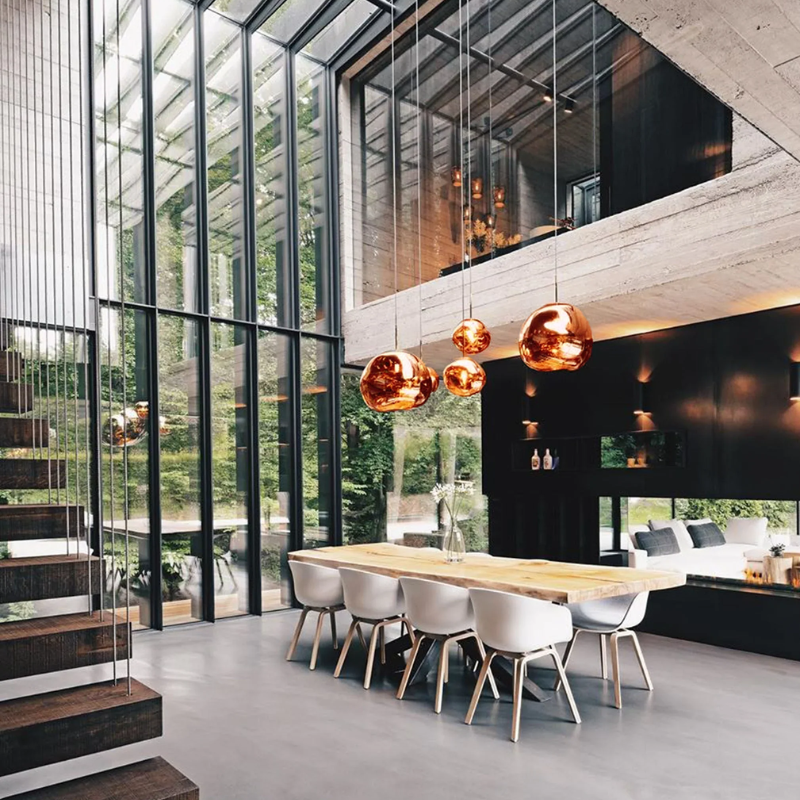 Modern dining area with Tom Dixon Melt pendants in copper over a table.