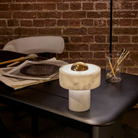 The Stone Portable Light by Tom Dixon in Brass on a desk.