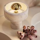 The Stone Portable Light by Tom Dixon in Brass on a bathroom vanity.