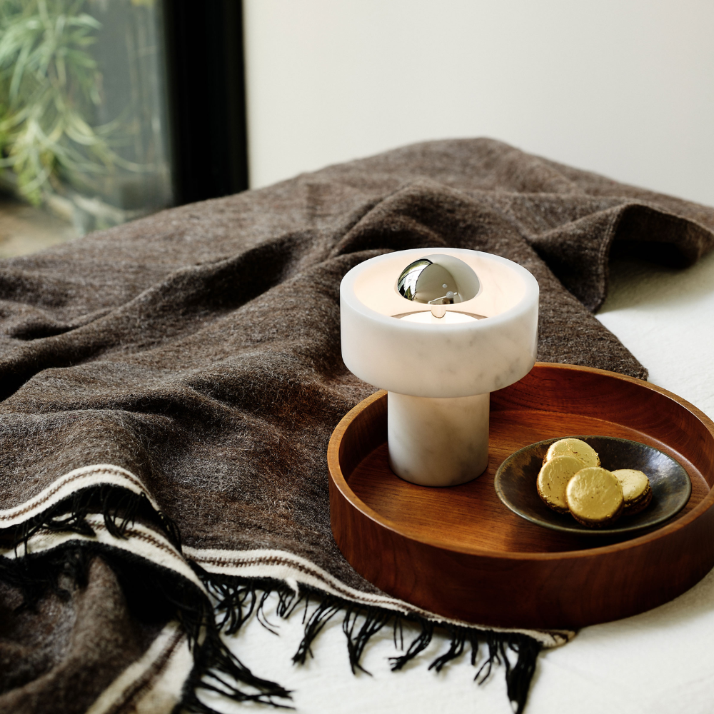 The Stone Portable Light by Tom Dixon in Silver on a tray.