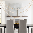 The Collier 108 Chandelier from Visual Comfort and Co in natural brass over a dining table.