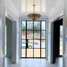 The Hampton Medium Chandelier from Visual Comfort and Co in antique gold in a living room.