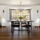 The Mollino Large Tiered Chandelier from Visual Comfort and Co in hand-rubbed antique brass in a dining room.