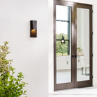 The Peak Outdoor Wall Sconce from Visual Comfort and Co outside beside a doorway entrance.