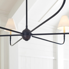 The Piaf Grande Chandelier from Visual Comfort & Co. in aged iron and ebonized oak in a lounge.