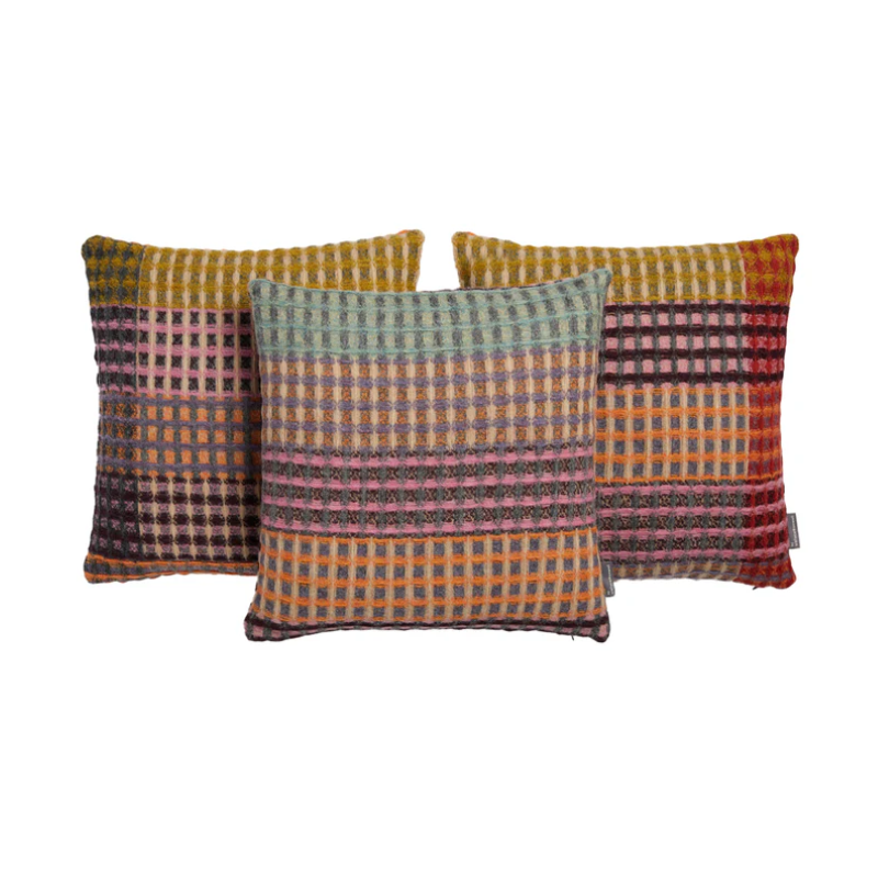 The Kew Cushion by Wallace and Sewell is made of natural shetland wool. Image showing three colorways of the same cushion.