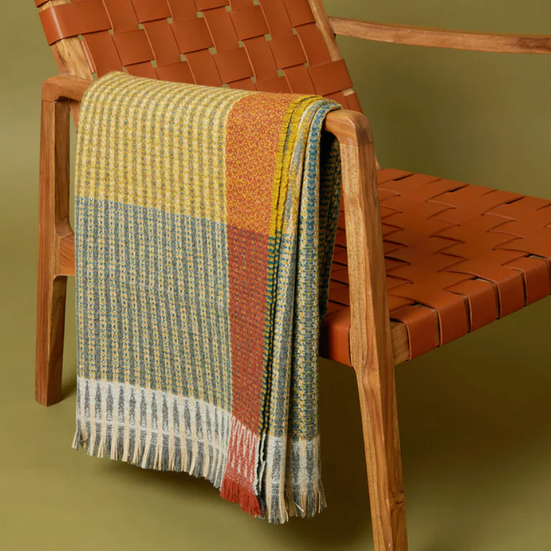 The Lismore Throw by Wallace & Sewell on the arm of a chair.