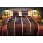 The Sophia Throw by Wallace & Sewell, size large on a bed with matching cushions.