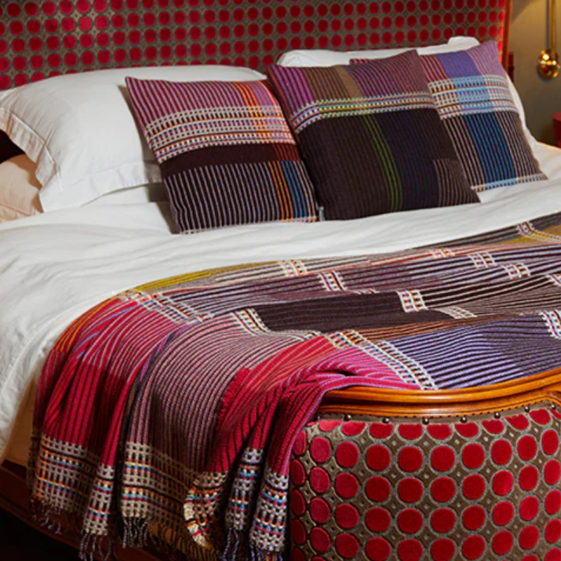 The Sophia Throw by Wallace & Sewell  with matching throw pillows on a bed.