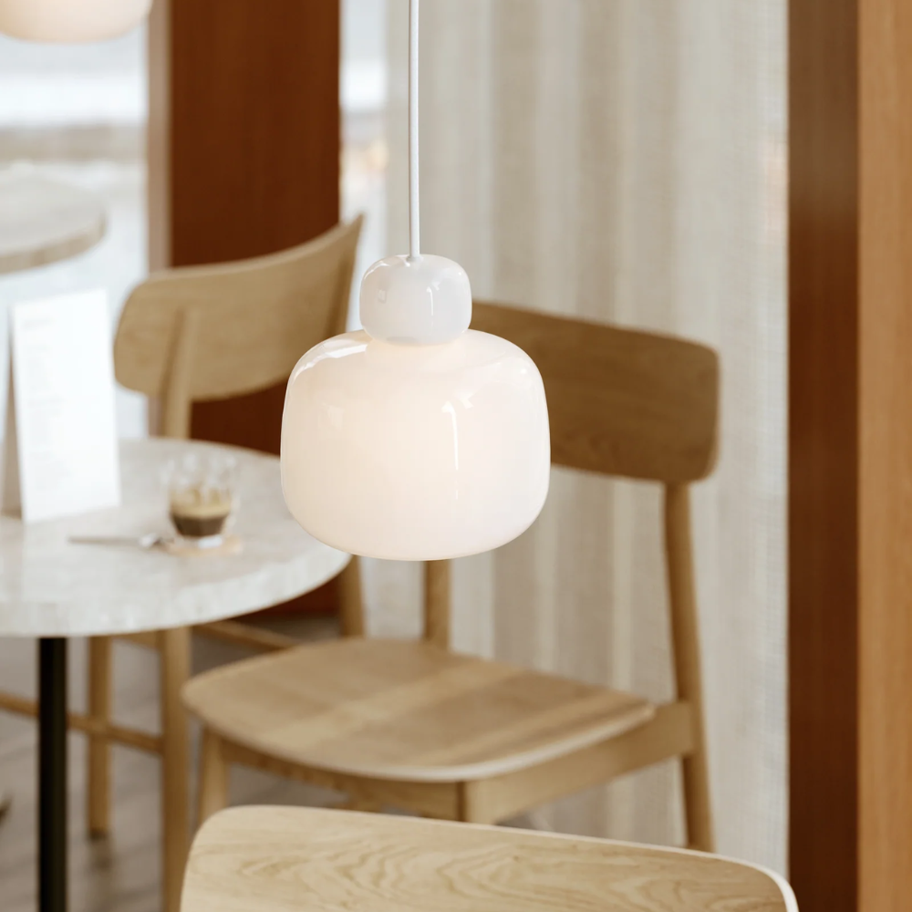 The Stone Glass Pendant in the size Small by Woud over a cafe table.