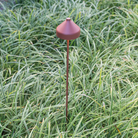 The terracotta Amelie Pro Garden Lamp from Zafferano outdoors in a garden with the top angled.
