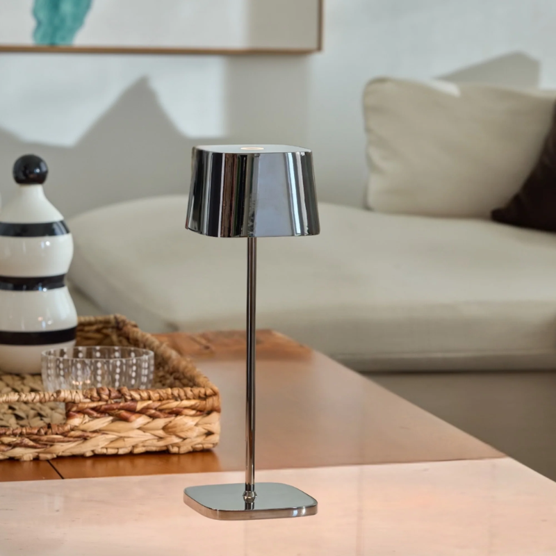The black chrome Ofelia Pro cordless lamp from Zafferano in a lounge area.