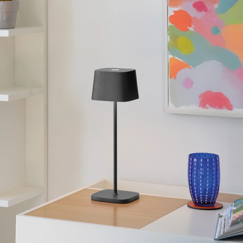 The dark gray Ofelia Pro cordless lamp from Zafferano in a living space.