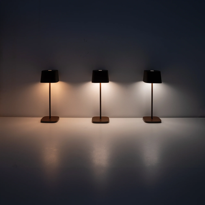 The rust Ofelia Pro cordless lamp from Zafferano showing the three color temperatures of the lamp.