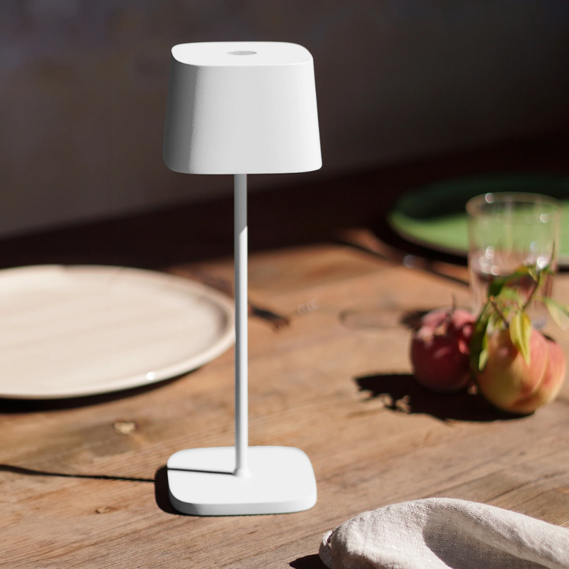 The white Ofelia Pro cordless lamp from Zafferano on a dining table.