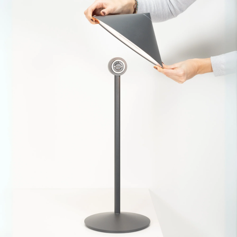 The titanium Pina L Desk Lamp from Zafferano hand holding the top head.