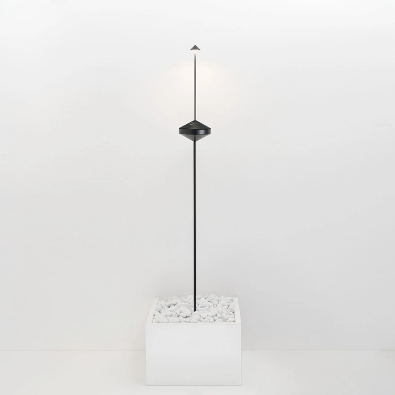 The black Pina Pro Floor Stand from Zafferano is standing in a white planter in a studio.