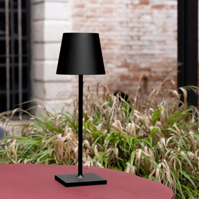 The black Poldina Pro L Desk Lamp from Zafferano in an outdoor living space.
