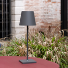 The dark gray Poldina Pro L Desk Lamp from Zafferano in an outdoor cafe.