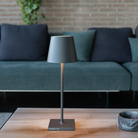The dark gray Poldina Pro L Desk Lamp from Zafferano in a living room.