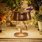 The anodized copper Sister Light Mini Wi-Fi Table Lamp from Zafferano on a dining table.