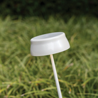 The pearl white Sister Light Wi-Fi Garden Lamp from Zafferano in a grassy outdoor garden.