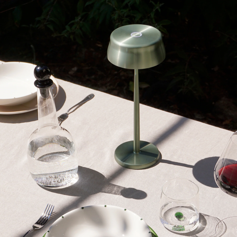 The anodized green Sister Light Wi-Fi Table Lamp from Zafferano is in the outdoor dining area.