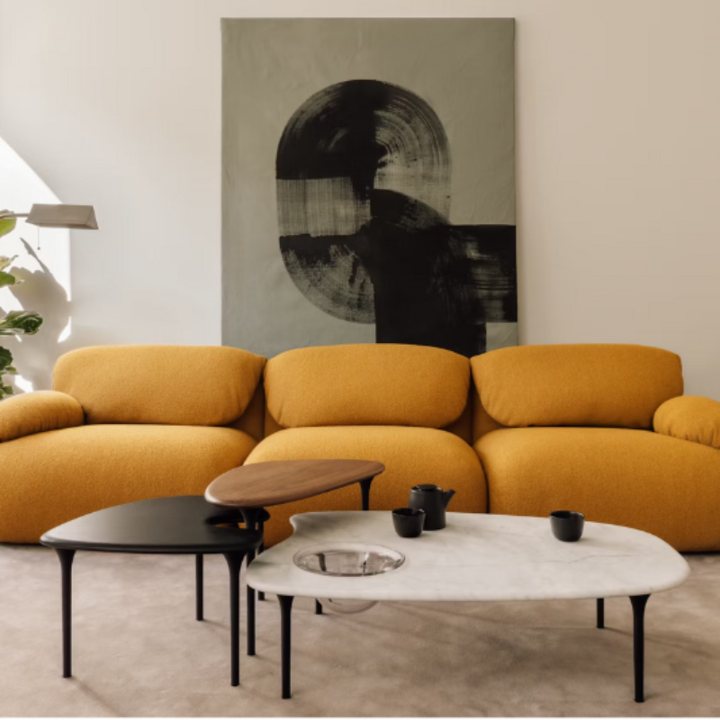 The low carrara marble table with bowl, mid black and high walnut Cyclade Tables from Herman Miller in a living space.
