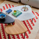 The low carrara marble with bowl, mid white oak and high black Cyclade Table from Herman Miller in a living room.