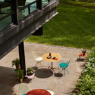 The Eames Dining Table from Herman Miller, designed by Herman Miller x Hay in a courtyard.