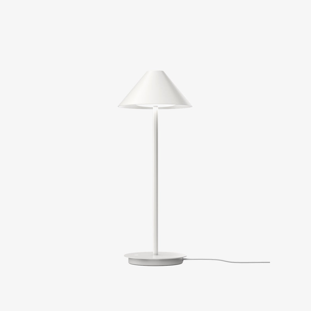 The Keglen table lamp’s distinctive conical shade has a built-in curved diffuser. This ensures an attractive and glare-free downwardly directed light. The stem morphs into the diffuser shade, folding inward and creating a beautiful organic geometry. A gentle light is also emitted upward through a discreet uniform opening in the top of the shade to create a perfect ambiance. Designed by Jakob Lange.
