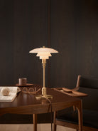 The PH 2/1 Table Lamp by Louis Poulsen features  three tiered mouth-blown glass shade and brass body. 