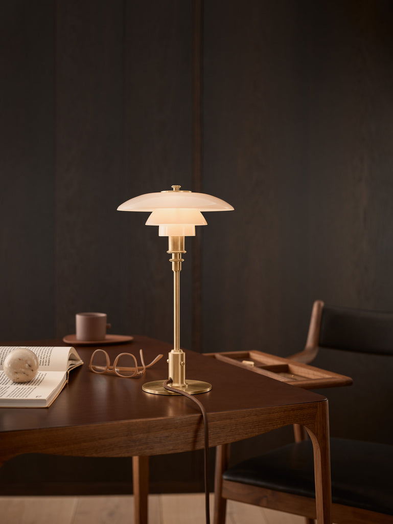 The PH 2/1 Table Lamp by Louis Poulsen features  three tiered mouth-blown glass shade and brass body. 