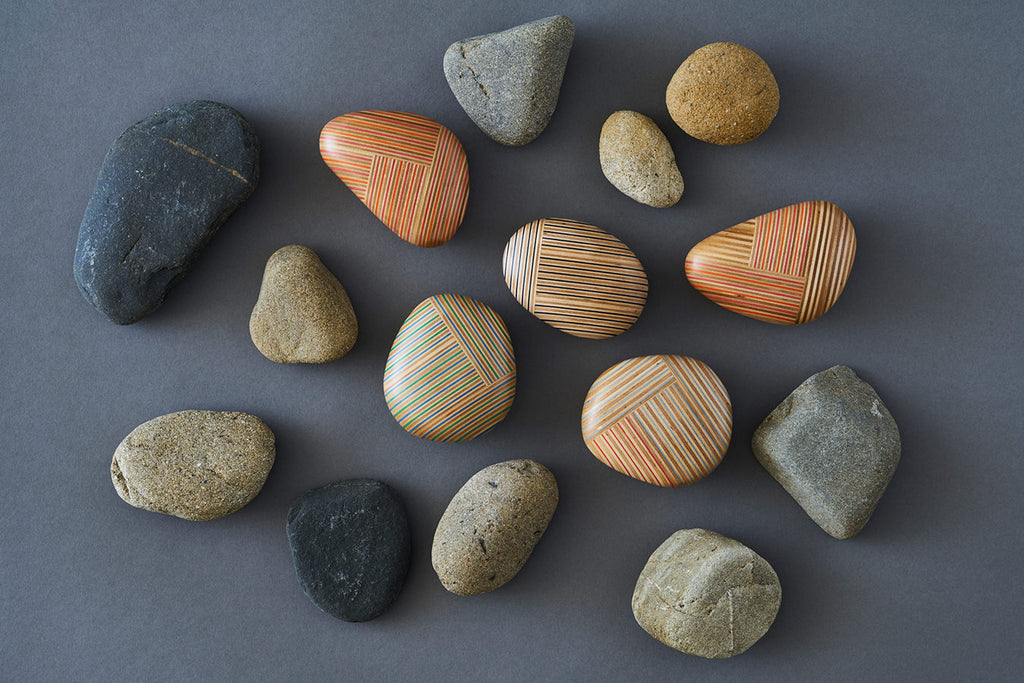 Pebble-like paperweights made by joining beautiful plywood pieces in a patchwork style. Designed by Drill Design.