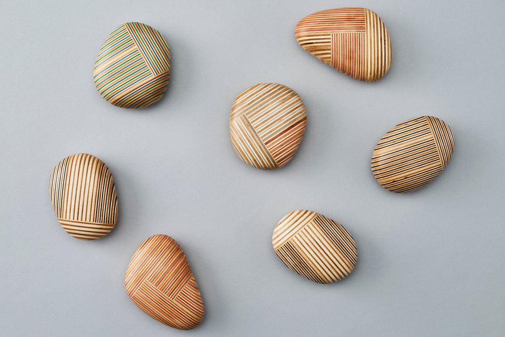 Pebble-like paperweights made by joining beautiful plywood pieces in a patchwork style. Designed by Drill Design.
