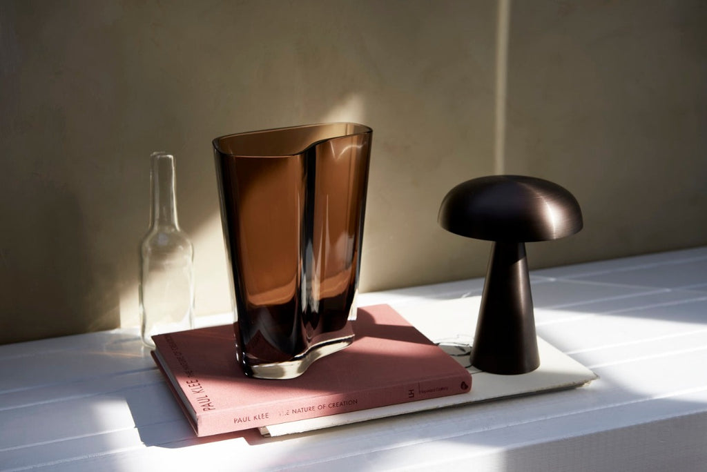 Como SC53, a portable table lamp from Space Copenhagen. Crafted from anodized aluminum, Como’s sturdy base tapers up towards a softy curved, mushroom-shaped shade. This battery-powered lamp can operate for eleven hours at the highest setting, with an extra battery option that allows additional operating. It is easily recharged with a magnetic USB cable or a charging tray.