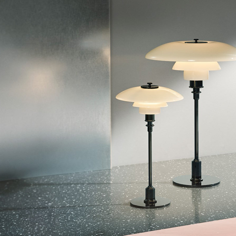 The PH 2/1 Table Light by Paul Henningsen for Louis Poulsen features a triple-layer hand blown glass shade that rests on a beautiful, lightly brushed brass frame, which references the original PH Table Lamp from 1927. Its design evokes timeless elegance with its use of classic materials. Complimenting environments both simple and eclectic, the PH 2/1 boasts a small profile making the lamp endlessly adaptable anywhere within the home, like on a windowsill or small table. 