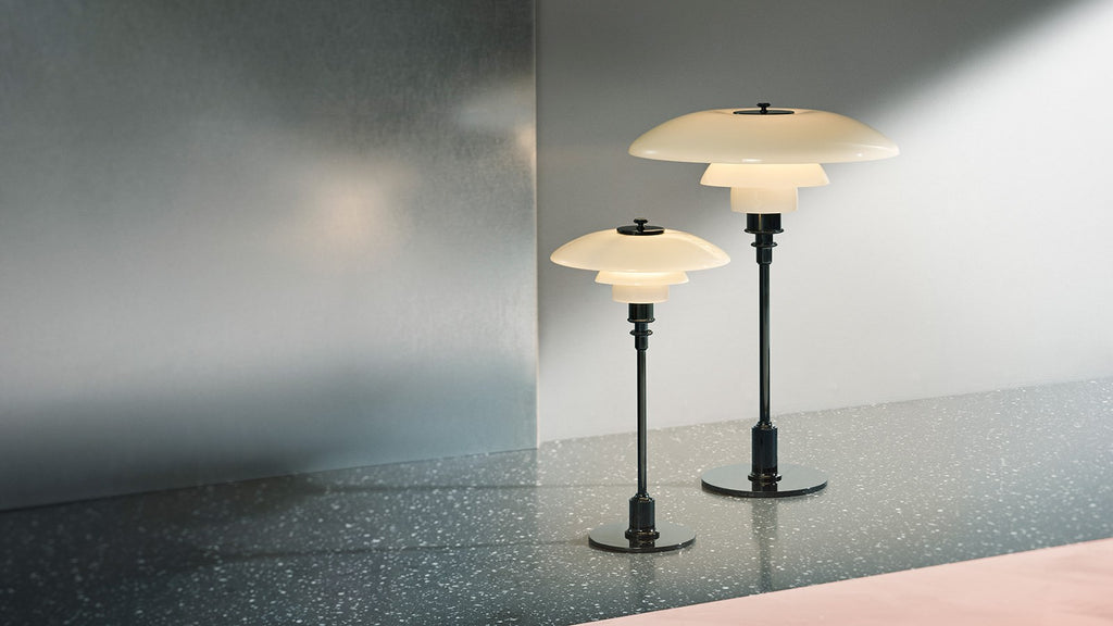 The PH 2/1 Table Light by Paul Henningsen for Louis Poulsen features a triple-layer hand blown glass shade that rests on a beautiful, lightly brushed brass frame, which references the original PH Table Lamp from 1927. Its design evokes timeless elegance with its use of classic materials. Complimenting environments both simple and eclectic, the PH 2/1 boasts a small profile making the lamp endlessly adaptable anywhere within the home, like on a windowsill or small table. 