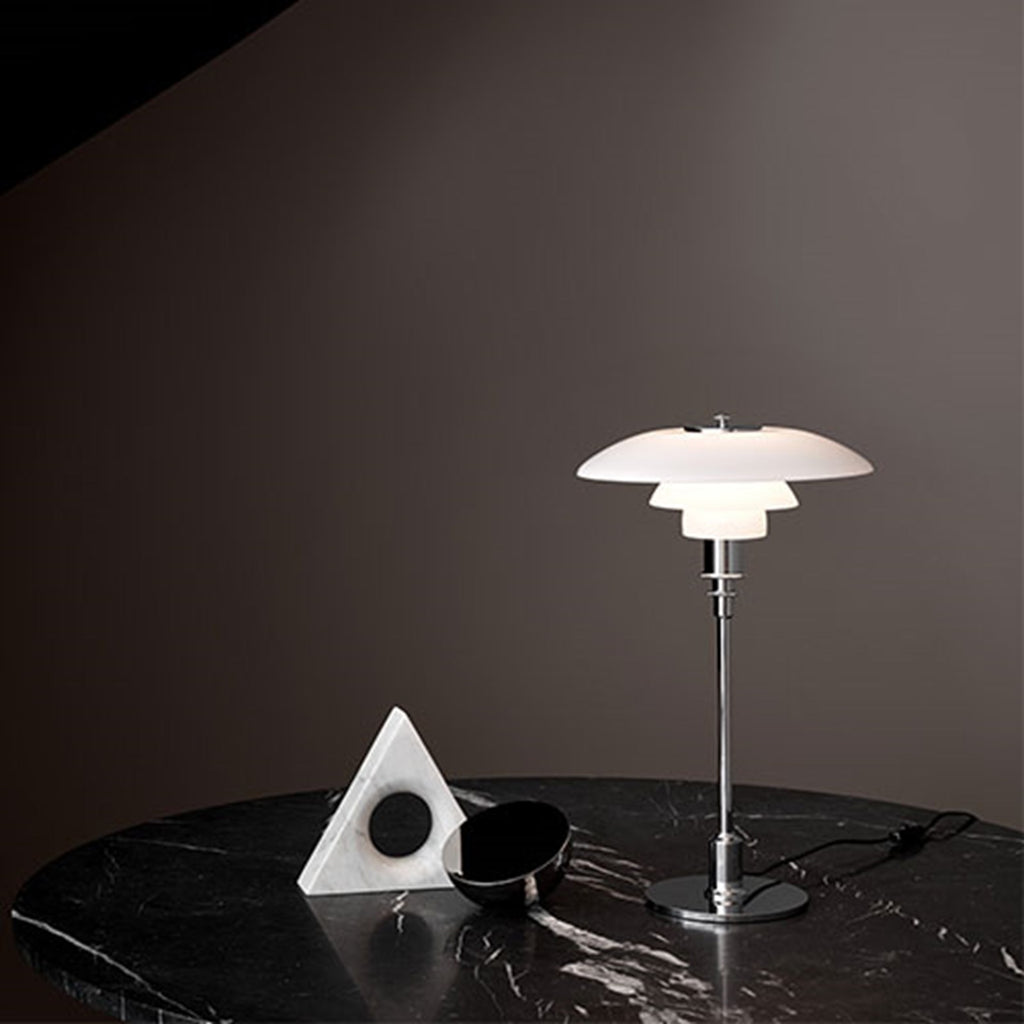 The PH 2/1 Table Light by Paul Henningsen for Louis Poulsen features a triple-layer hand blown glass shade that rests on a beautiful, lightly brushed brass frame, which references the original PH Table Lamp from 1927. Its design evokes timeless elegance with its use of classic materials. Complimenting environments both simple and eclectic, the PH 2/1 boasts a small profile making the lamp endlessly adaptable anywhere within the home, like on a windowsill or small table. 