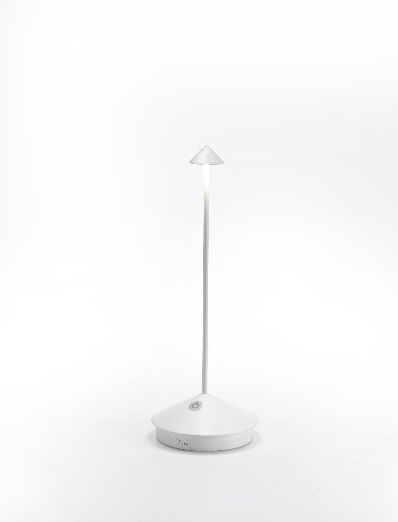 The Pina Pro Rechargeable Lamp by Ai Lati for Zafferano features a sleek and small body and wide base to anchor the lamp. Its clean design perfectly suits small settings offering a crisp and bright light to a space. Features a die-cast LED lamp with polycarbonate diffuser, 13+ hours of rechargeable battery life, and portable body makes the Pina Pro an excellent accents to a space. Touch-dimmable. Contact charging base with USB cable included. Suitable for indoor or outdoor use.