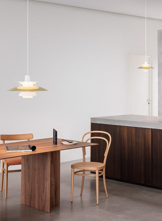 The PH 5 Pendant Light by Louis Poulsen in Brass over a wooden dining table